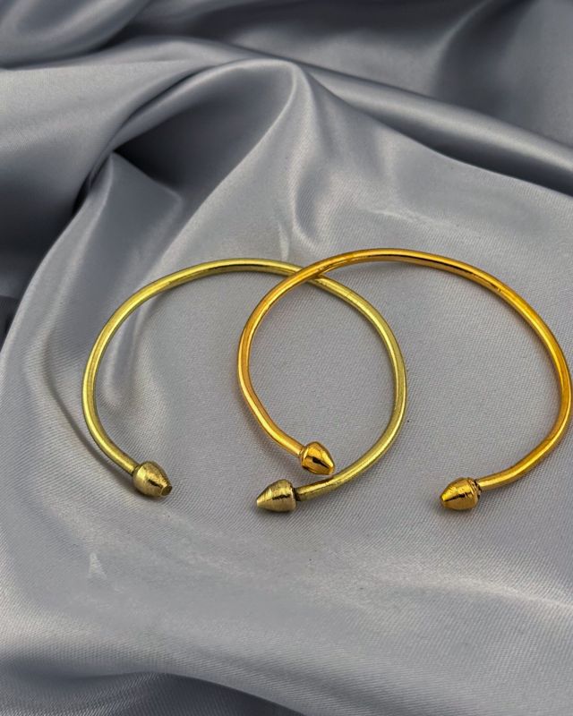 Zwei vergoldete Armreifen in einem helleren und einem kräftigeren Goldton
